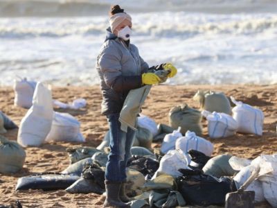 Активистка собирает в мусорные мешки загрязненный мазутом песок. Фото: anapaofficial / Telegram Активистка собирает в мусорные мешки загрязненный мазутом песок. Фото: anapaofficial / Telegram